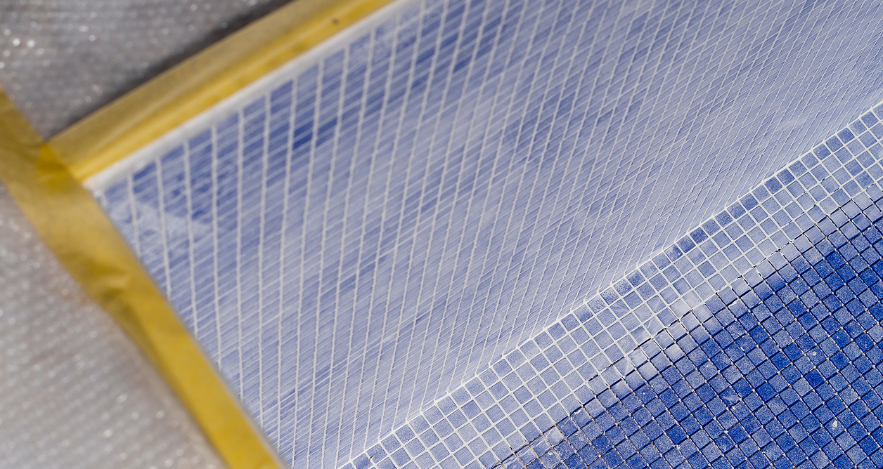 Blue mosaic tiles with yellow masking tape during a swimming pool renovation.