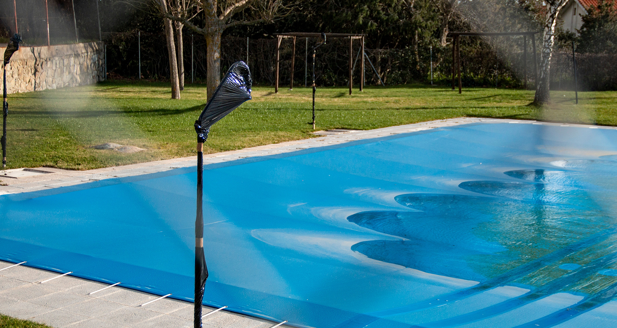 Blue pool cover on an outdoor swimming pool with water misting system.