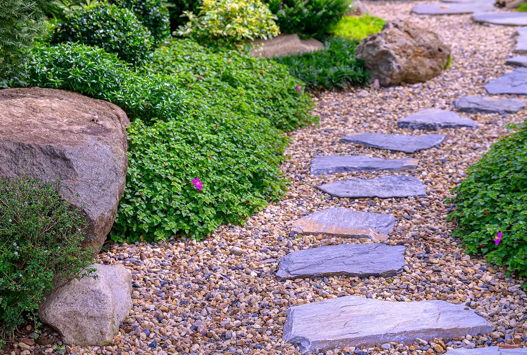 Stone and timber garden steps leading up a grassy hill with lights.