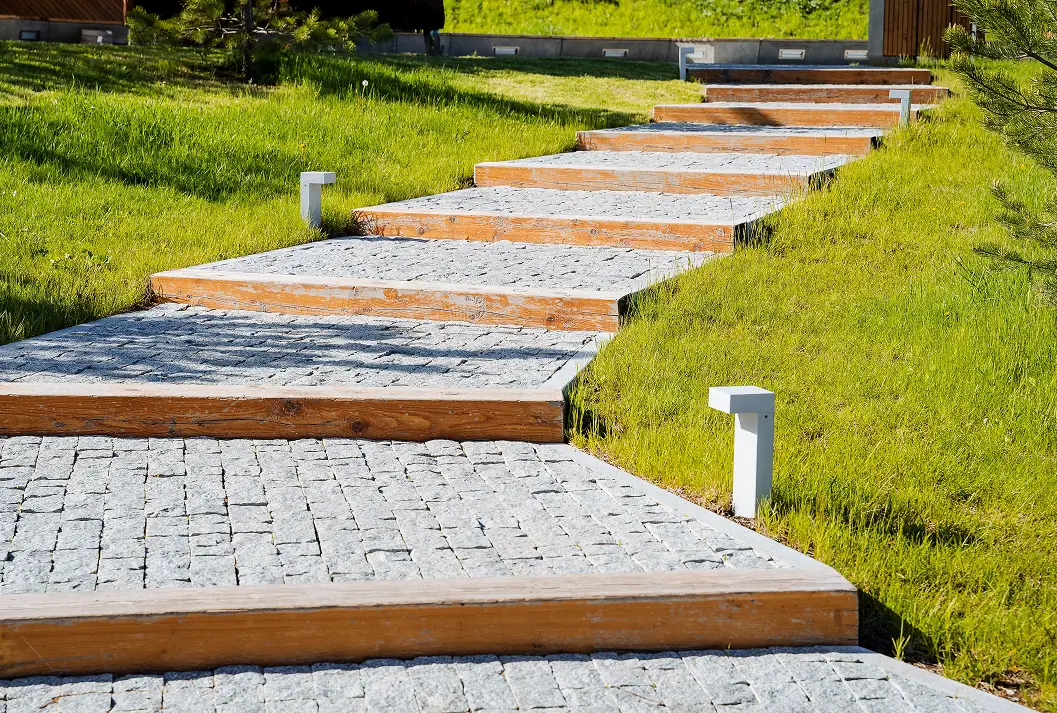 Landscaper installing large white concrete stepping stones in a yard.