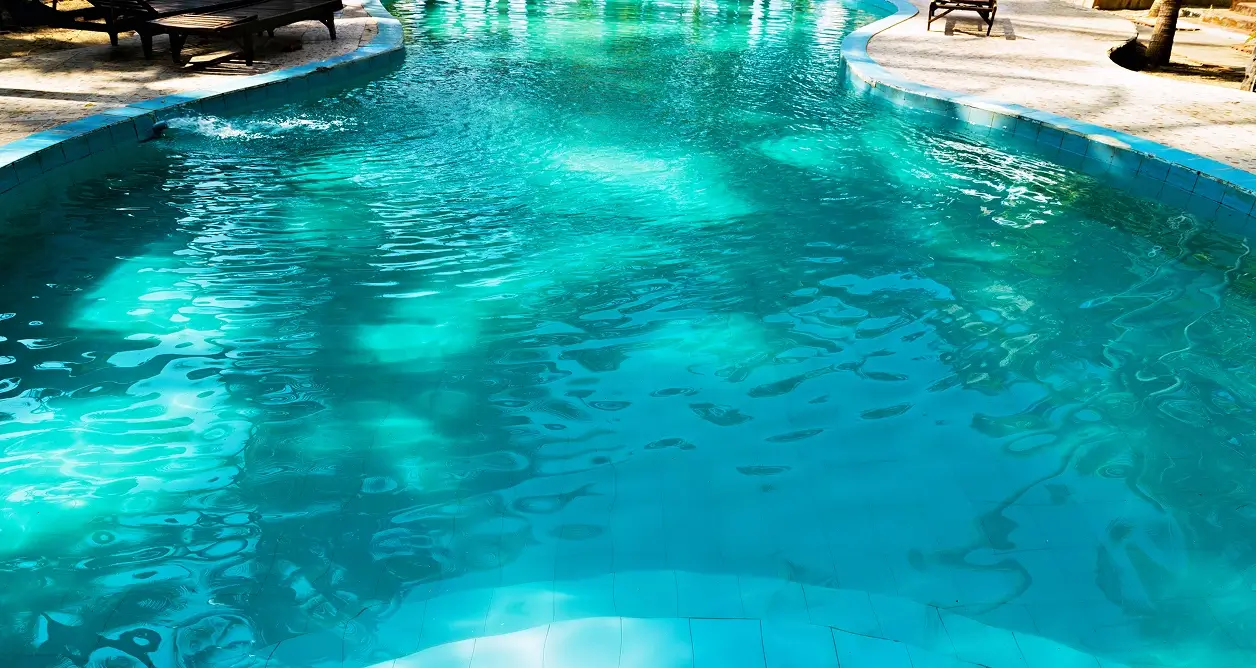 Turquoise swimming pool with shimmering water and a stone patio.