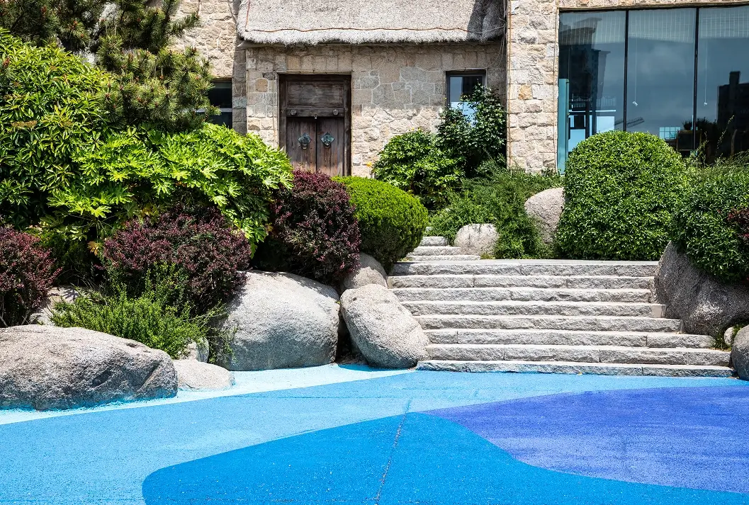 Wide stone steps leading up to a stone building with large landscaping boulders.